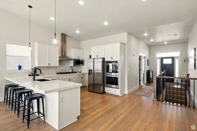1335 S 1140 E, Heber City, UT 84032 - kitchen featuring appliances with stainless steel finishes, wall chimney exhaust hood, a sink, a breakfast bar, and light wood finished floors