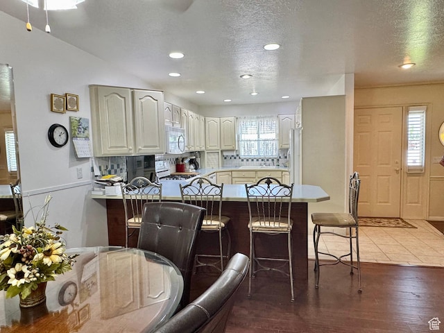 786 E Bristlecone Dr, Delta, UT 84624 - kitchen with white stove, a peninsula, a breakfast bar area, decorative backsplash, and a textured ceiling