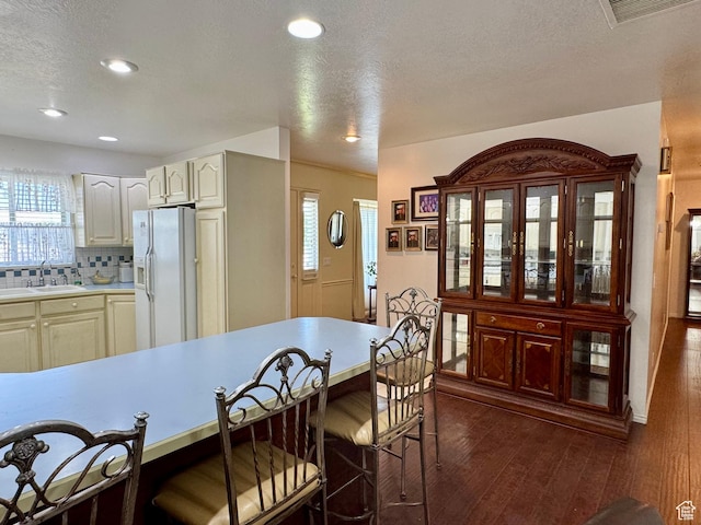 786 E Bristlecone Dr, Delta, UT 84624 - kitchen featuring white fridge with ice dispenser, light countertops, a textured ceiling, a kitchen bar, and decorative backsplash