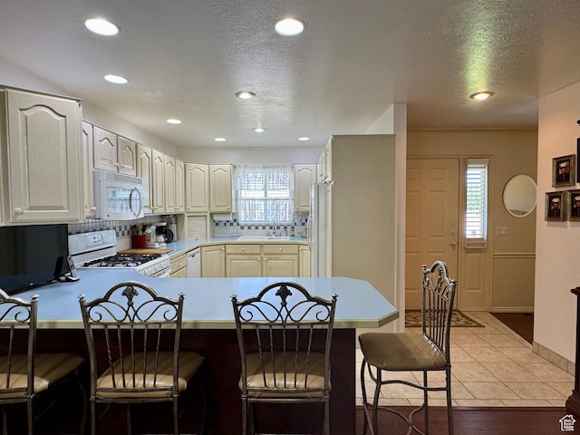 786 E Bristlecone Dr, Delta, UT 84624 - kitchen with white appliances, a peninsula, a breakfast bar area, tasteful backsplash, and recessed lighting