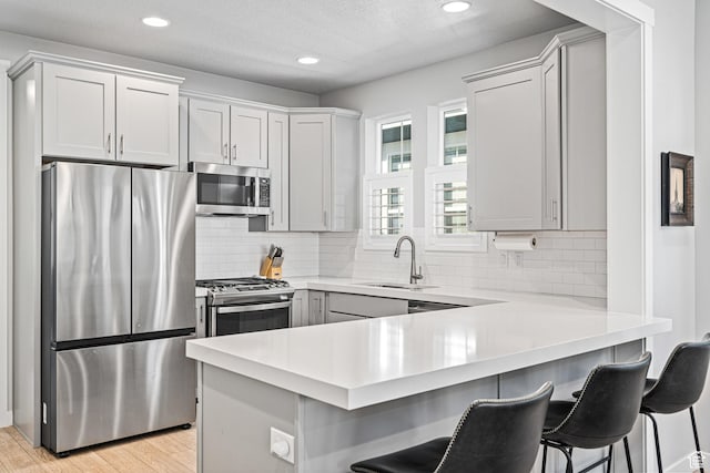 9857 N Featherstone Dr, Highland, UT 84003 - kitchen featuring appliances with stainless steel finishes, a sink, a peninsula, a kitchen breakfast bar, and light countertops
