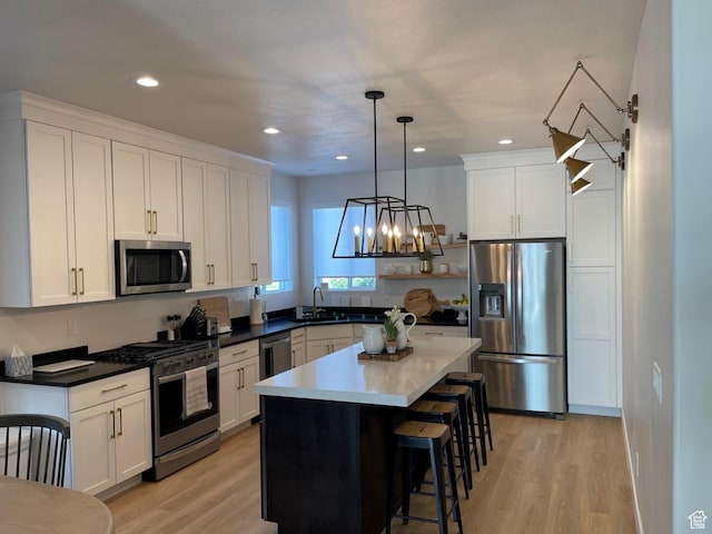 858 N Pinehurst Dr, Midway, UT 84049 - kitchen featuring appliances with stainless steel finishes, light wood finished floors, a kitchen bar, white cabinets, and a center island