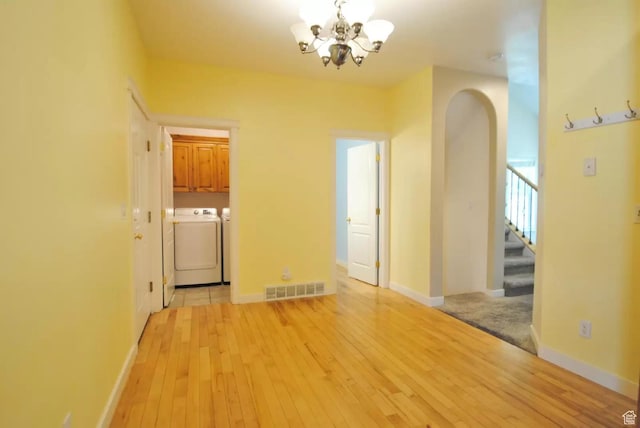 1035 N 130 W Unit 100, Logan, UT 84341 - empty room featuring washing machine and dryer, a chandelier, stairway, light wood-type flooring, and arched walkways