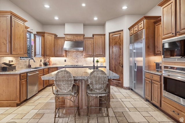 3052 N Snow Canyon Pwky Unit 168, St George, UT 84770 - kitchen featuring built in appliances, a sink, exhaust hood, a center island with sink, and stone tile flooring