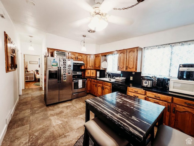 1 S 3rd Ave, Helper, UT 84526 - kitchen with appliances with stainless steel finishes, under cabinet range hood, brown cabinetry, dark countertops, and a ceiling fan