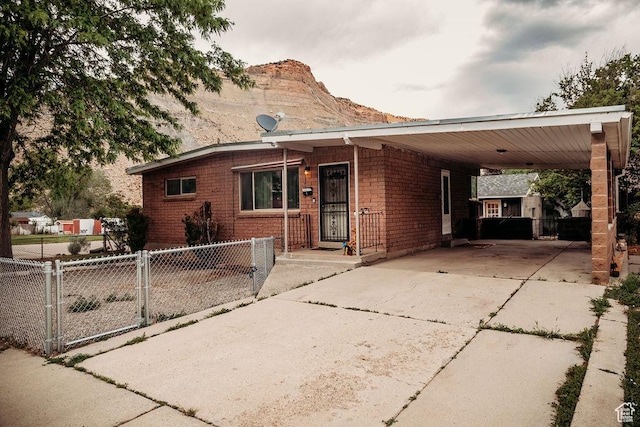 1 S 3rd Ave, Helper, UT 84526 - view of front of house with concrete driveway, an attached carport, a gate, a mountain view, and brick siding