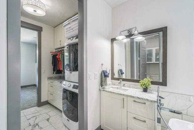 1186 W Marinwood Ave, Murray, UT 84123 - bathroom with stacked washer / drying machine, marble look tile flooring, vanity, and baseboards