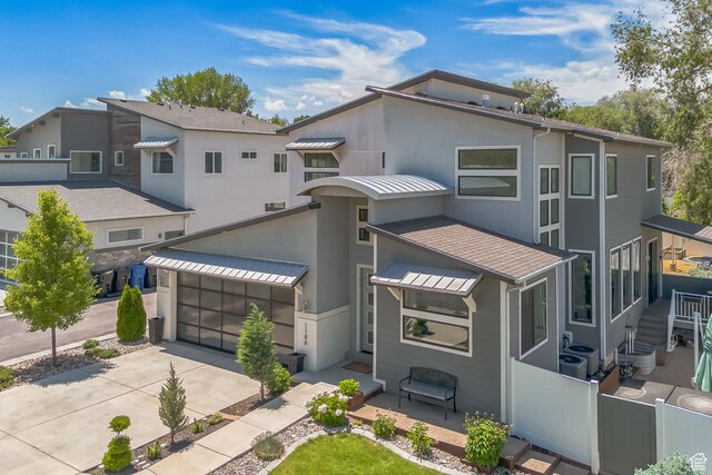 1186 W Marinwood Ave, Murray, UT 84123 - view of front of home with concrete driveway, a standing seam roof, stucco siding, and a garage