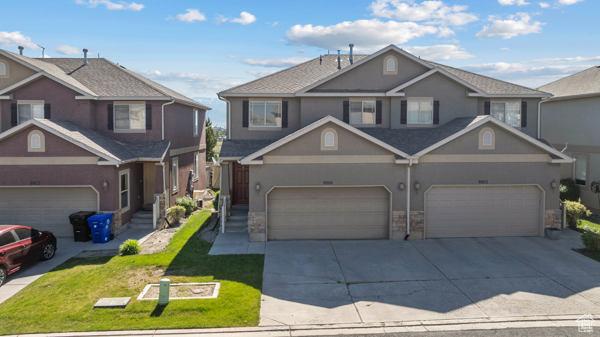 8064 N Clearwater Rd, Eagle Mountain, UT 84005 - traditional-style home featuring driveway, stucco siding, a garage, a front lawn, and stone siding