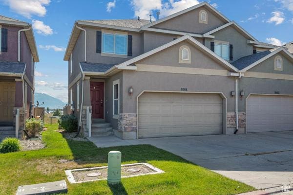 8064 N Clearwater Rd, Eagle Mountain, UT 84005 - view of front of home with stucco siding, driveway, stone siding, and an attached garage