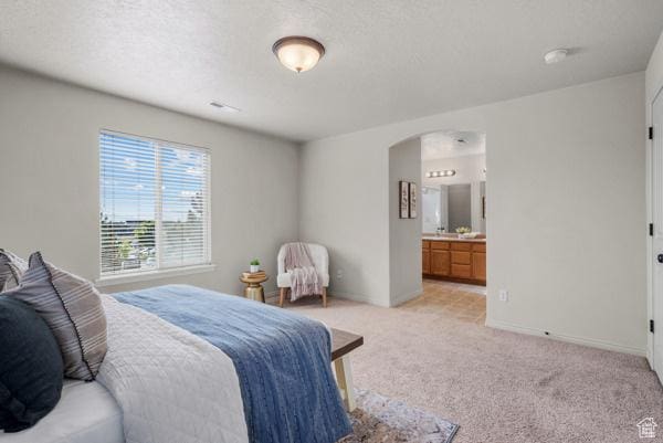 8064 N Clearwater Rd, Eagle Mountain, UT 84005 - bedroom featuring arched walkways, light colored carpet, a textured ceiling, baseboards, and ensuite bathroom
