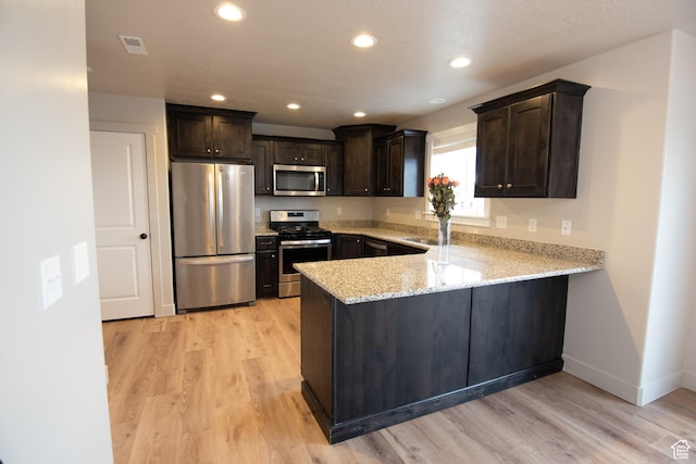 182 W Braeburn Ln, Santaquin, UT 84655 - kitchen featuring appliances with stainless steel finishes, dark brown cabinetry, a peninsula, light stone countertops, and recessed lighting