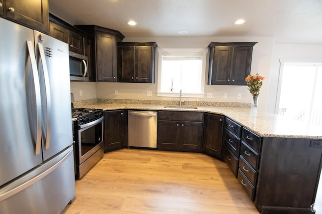 182 W Braeburn Ln, Santaquin, UT 84655 - kitchen with appliances with stainless steel finishes, a sink, a peninsula, light wood-style flooring, and dark brown cabinetry