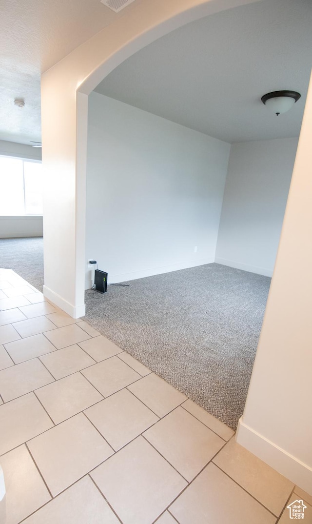 182 W Braeburn Ln, Santaquin, UT 84655 - carpeted empty room featuring arched walkways, tile patterned floors, and baseboards