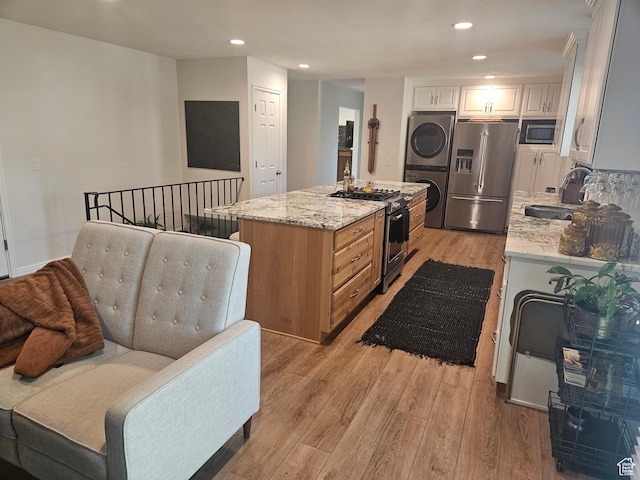5235 S Spring Clover Dr W, Salt Lake City, UT 84123 - kitchen with appliances with stainless steel finishes, a sink, stacked washer and clothes dryer, light wood finished floors, and a kitchen island