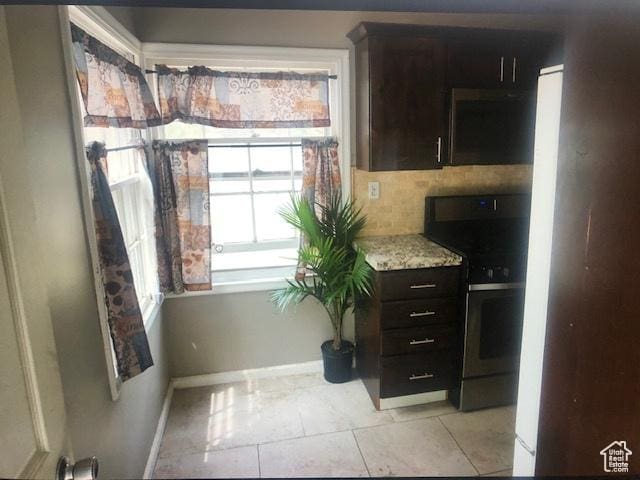 2726 S Cyprus Ln, Magna, UT 84044 - kitchen featuring stainless steel range, baseboards, light tile patterned floors, dark brown cabinets, and light stone counters