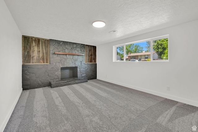 6034 S 2900 W, Roy, UT 84067 - unfurnished living room with a textured ceiling, baseboards, a stone fireplace, and carpet floors