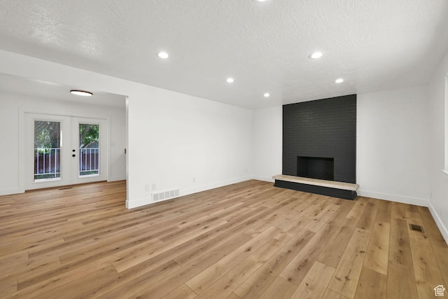 6034 S 2900 W, Roy, UT 84067 - unfurnished living room featuring a textured ceiling, light wood-style flooring, french doors, a brick fireplace, and recessed lighting