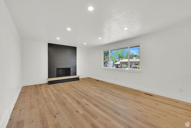 6034 S 2900 W, Roy, UT 84067 - unfurnished living room with a fireplace, recessed lighting, light wood-style floors, baseboards, and a textured ceiling
