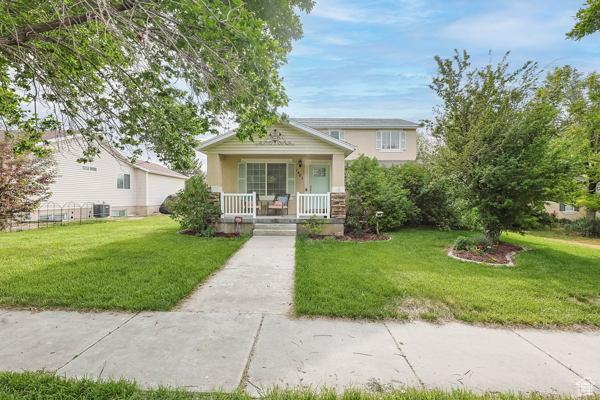 1405 N Durocher Ln W, Tooele, UT 84074 - view of front of house with covered porch, stucco siding, a front lawn, and central air condition unit