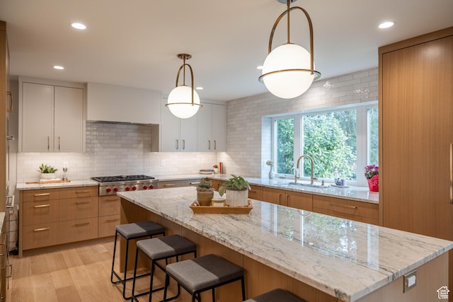 3563 S Canyon Way, Millcreek, UT 84106 - kitchen featuring stainless steel gas stovetop, decorative backsplash, a breakfast bar area, recessed lighting, and light stone countertops