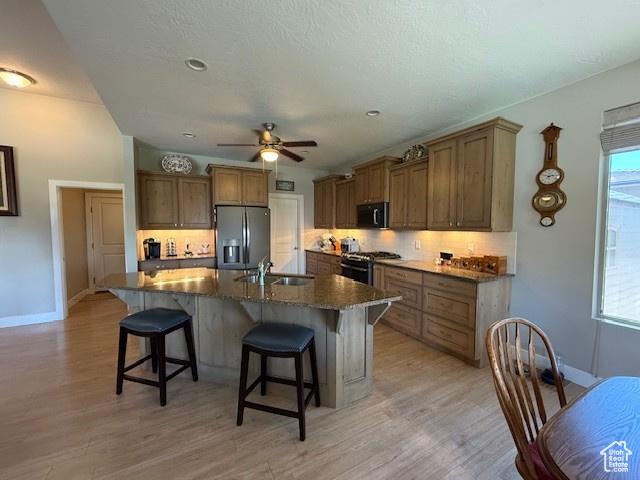 1523 E Talus Way, St George, UT 84790 - kitchen with stainless steel fridge with ice dispenser, gas stove, a sink, tasteful backsplash, and a breakfast bar area