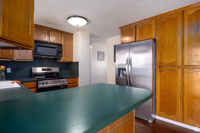 1878 S 3300 W, Syracuse, UT 84075 - kitchen with appliances with stainless steel finishes, brown cabinetry, dark wood-style flooring, a textured ceiling, and dark countertops