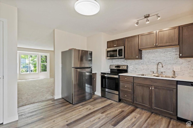 1622 W 8740 S, West Jordan, UT 84088 - kitchen with appliances with stainless steel finishes, a sink, light wood-style floors, dark brown cabinetry, and backsplash