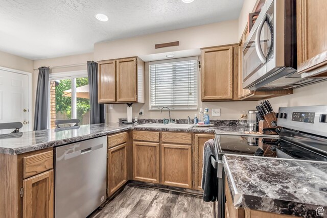 2316 E Claybourne Ave S, Millcreek, UT 84109 - kitchen featuring appliances with stainless steel finishes, a sink, a peninsula, light wood-type flooring, and a textured ceiling