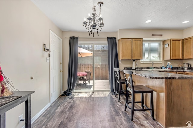 2316 E Claybourne Ave S, Millcreek, UT 84109 - kitchen featuring a chandelier, a textured ceiling, dark wood-type flooring, baseboards, and a breakfast bar area