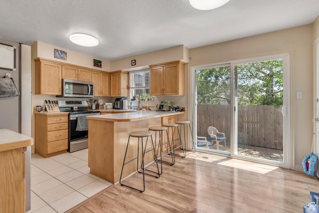 2316 E Claybourne Ave S, Millcreek, UT 84109 - kitchen featuring appliances with stainless steel finishes, light countertops, a kitchen bar, a peninsula, and a textured ceiling