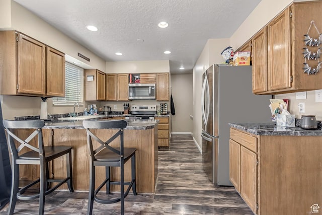 2316 E Claybourne Ave S, Millcreek, UT 84109 - kitchen featuring stainless steel appliances, a peninsula, a textured ceiling, a sink, and a breakfast bar area