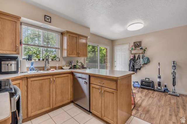 2316 E Claybourne Ave S, Millcreek, UT 84109 - kitchen featuring stainless steel appliances, a peninsula, a sink, light countertops, and a textured ceiling