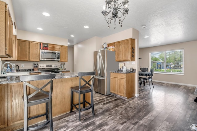 2316 E Claybourne Ave S, Millcreek, UT 84109 - kitchen featuring appliances with stainless steel finishes, recessed lighting, dark wood-style floors, a kitchen bar, and a textured ceiling