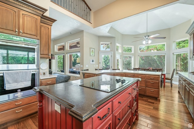 1287 W Bloomington Dr S Unit 7, Bloomington, UT 84790 - kitchen with black electric stovetop, a kitchen island, stainless steel double oven, plenty of natural light, and a high ceiling