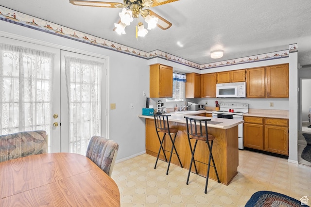 4924 W Barton Park Dr, West Jordan, UT 84081 - kitchen featuring white appliances, light floors, brown cabinets, light countertops, and a ceiling fan