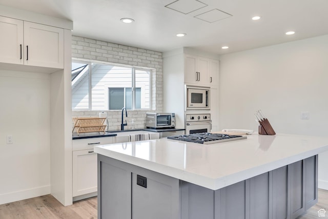 1474 E Rock View Ct, Kamas, UT 84036 - kitchen featuring oven, a sink, stainless steel microwave, light wood-style flooring, and white cabinets