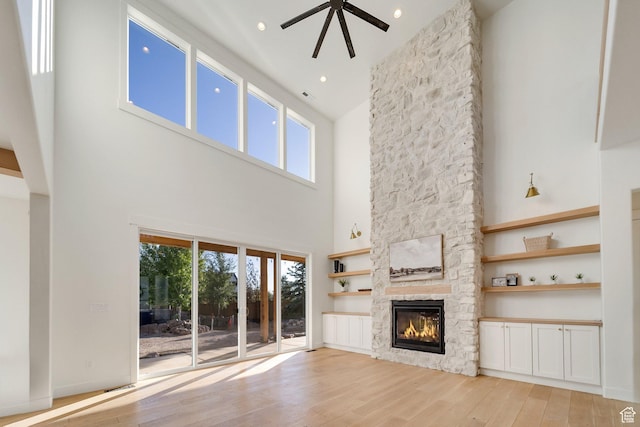 1474 E Rock View Ct, Kamas, UT 84036 - unfurnished living room with a towering ceiling, a fireplace, light wood-type flooring, healthy amount of natural light, and a ceiling fan