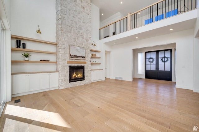 1474 E Rock View Ct, Kamas, UT 84036 - unfurnished living room featuring light wood-style flooring, a fireplace, a high ceiling, and french doors