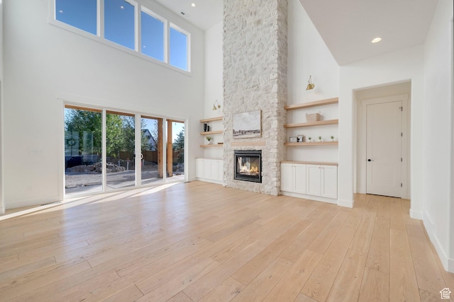 1474 E Rock View Ct, Kamas, UT 84036 - unfurnished living room with a towering ceiling, light wood-style floors, a fireplace, and healthy amount of natural light