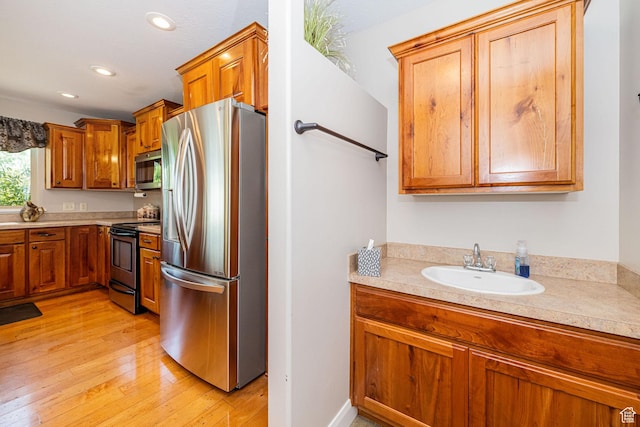 1257 W 3275 S, Perry, UT 84302 - kitchen featuring stainless steel appliances, light countertops, a sink, light wood-style flooring, and brown cabinetry