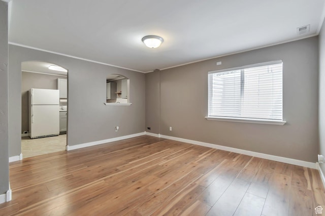 8567 S Cork Oak Dr, West Jordan, UT 84081 - empty room featuring light wood-type flooring, baseboards, ornamental molding, and arched walkways