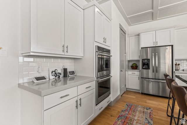 6653 W Dry Creek Ln, Highland, UT 84003 - kitchen with appliances with stainless steel finishes, decorative backsplash, white cabinets, and light wood-style flooring