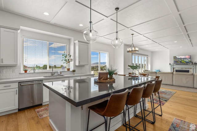 6653 W Dry Creek Ln, Highland, UT 84003 - kitchen with stainless steel dishwasher, a sink, tasteful backsplash, a breakfast bar, and light wood finished floors