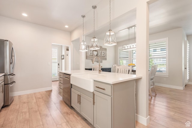 10773 S Beach Comber Way S, Jordan, UT 84009 - kitchen with stainless steel appliances, a sink, light wood finished floors, light countertops, and decorative light fixtures