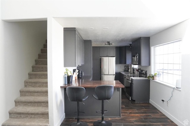 1204 Hyperion Way, Soda Springs, ID 83276 - kitchen with appliances with stainless steel finishes, gray cabinets, baseboards, dark wood-style flooring, and a peninsula