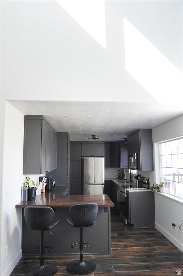 1204 Hyperion Way, Soda Springs, ID 83276 - kitchen with stainless steel appliances, a peninsula, dark wood-style floors, a kitchen bar, and baseboards