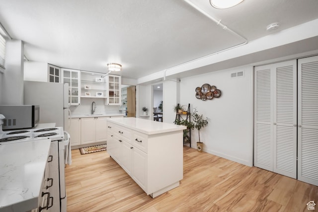 1377 E Wilson Ave, Salt Lake City, UT 84105 - kitchen with stainless steel microwave, a sink, white range with electric stovetop, light wood-type flooring, and white cabinets