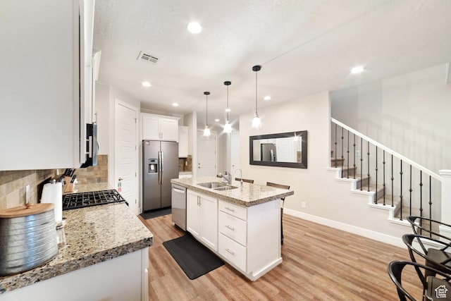 5048 N Escapes Dr, St George, UT 84770 - kitchen featuring appliances with stainless steel finishes, a sink, light wood finished floors, tasteful backsplash, and white cabinetry