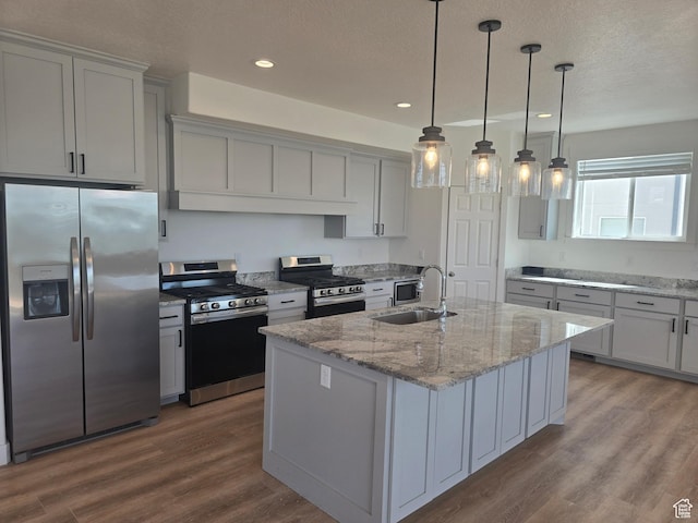 1573 N Woodside Dr, Spanish Fork, UT 84660 - kitchen with stainless steel appliances, a sink, dark wood-style floors, a textured ceiling, and a center island with sink